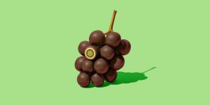 Foto einer Traube, an der statt Beeren Mozartkugeln hängen auf grünem Untergrund